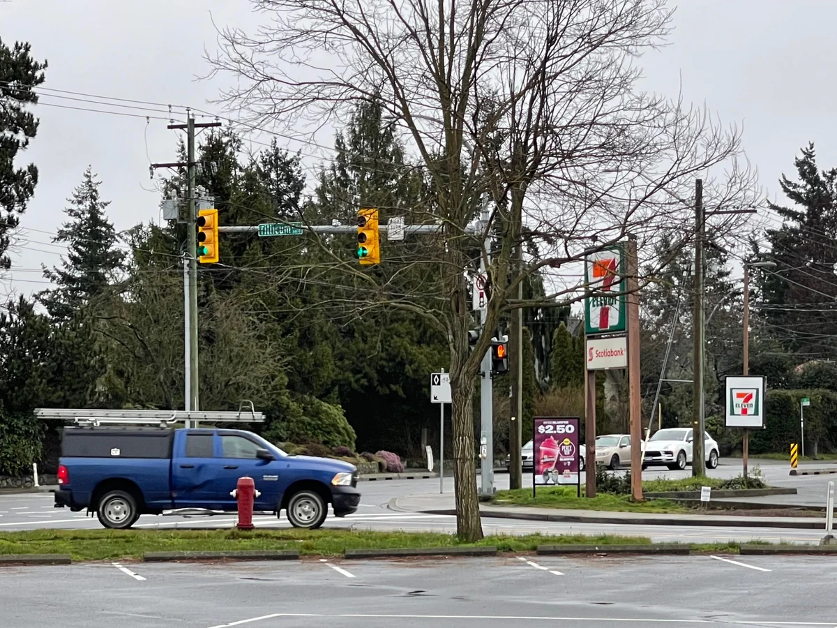 A suburban intersection at Tillicum Road on an overcast day, with traffic signals, a blue pickup truck, and 7-Eleven and Scotiabank signs on the far corner.